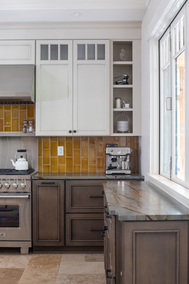 Medium sized eclectic l-shaped kitchen/diner in Milwaukee with a belfast sink, recessed-panel cabinets, brown cabinets, granite worktops, yellow splashback, metro tiled splashback, stainless steel appliances, travertine flooring, an island, yellow floors and green worktops.