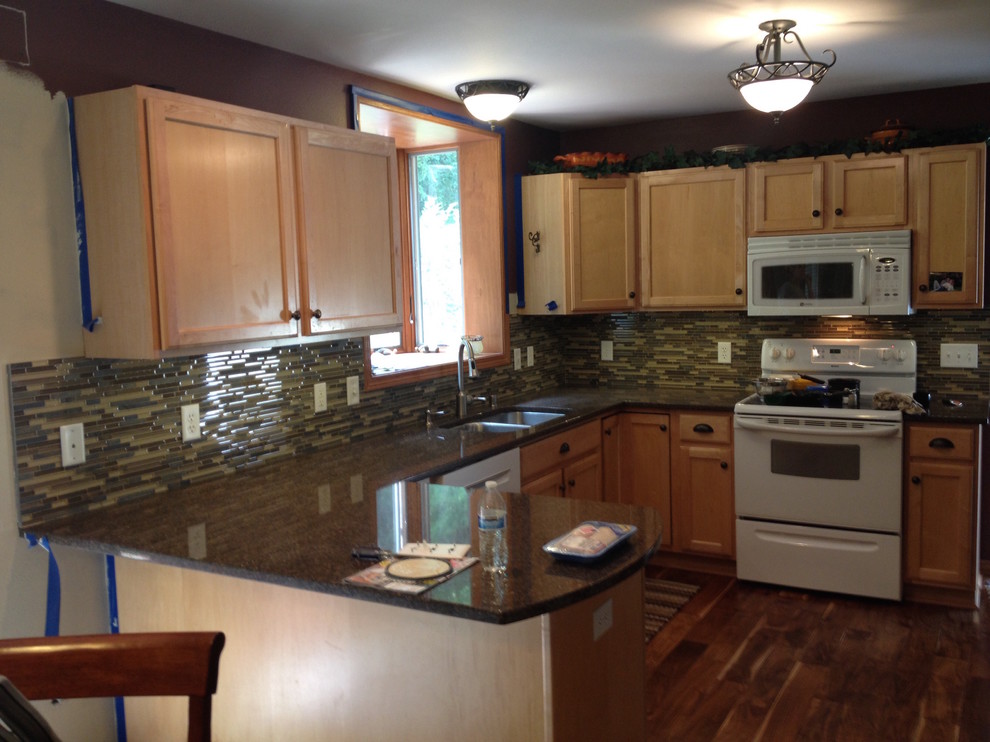 Inspiration for a transitional medium tone wood floor kitchen remodel with a double-bowl sink, recessed-panel cabinets, light wood cabinets, multicolored backsplash, matchstick tile backsplash, white appliances and a peninsula