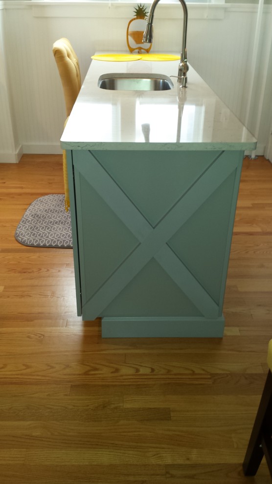 Example of a small transitional u-shaped light wood floor enclosed kitchen design in New York with an undermount sink, shaker cabinets, white cabinets, solid surface countertops, gray backsplash, subway tile backsplash, stainless steel appliances and an island