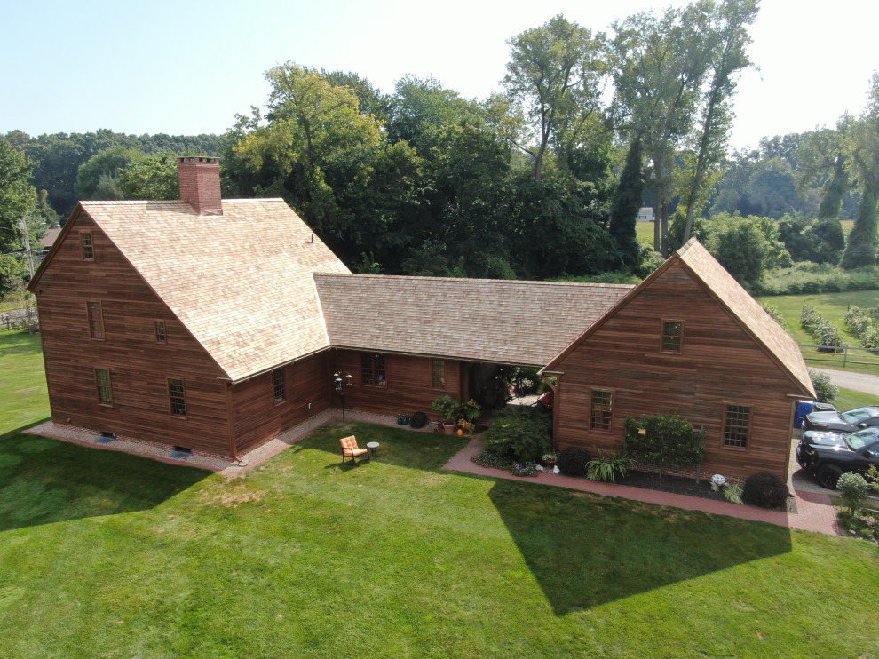 Réalisation d'une grande façade de maison marron champêtre en bois et bardage à clin à deux étages et plus avec un toit à deux pans, un toit en shingle et un toit rouge.
