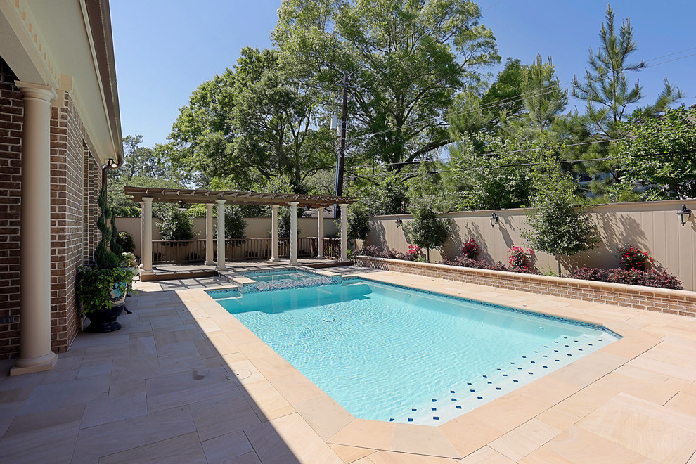 Large traditional backyard rectangular pool in Houston with a hot tub and natural stone pavers.