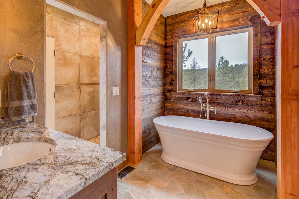 Design ideas for a country bathroom in Denver with medium wood cabinets, a freestanding tub, beige tile, brown walls, an undermount sink, beige floor and grey benchtops.
