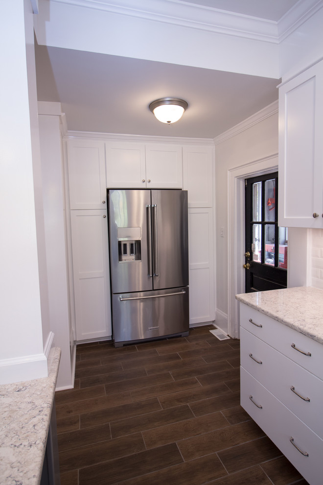 Example of a small u-shaped ceramic tile eat-in kitchen design with an undermount sink, shaker cabinets, white cabinets, quartz countertops, white backsplash, subway tile backsplash, stainless steel appliances, an island and white countertops