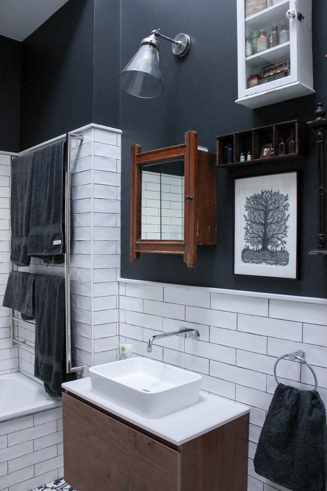 Photo of a contemporary bathroom in Sydney with flat-panel cabinets, brown cabinets, a drop-in tub, a shower/bathtub combo, white tile, ceramic tile, multi-coloured walls, ceramic floors, a wall-mount sink, engineered quartz benchtops, black floor, a hinged shower door and white benchtops.