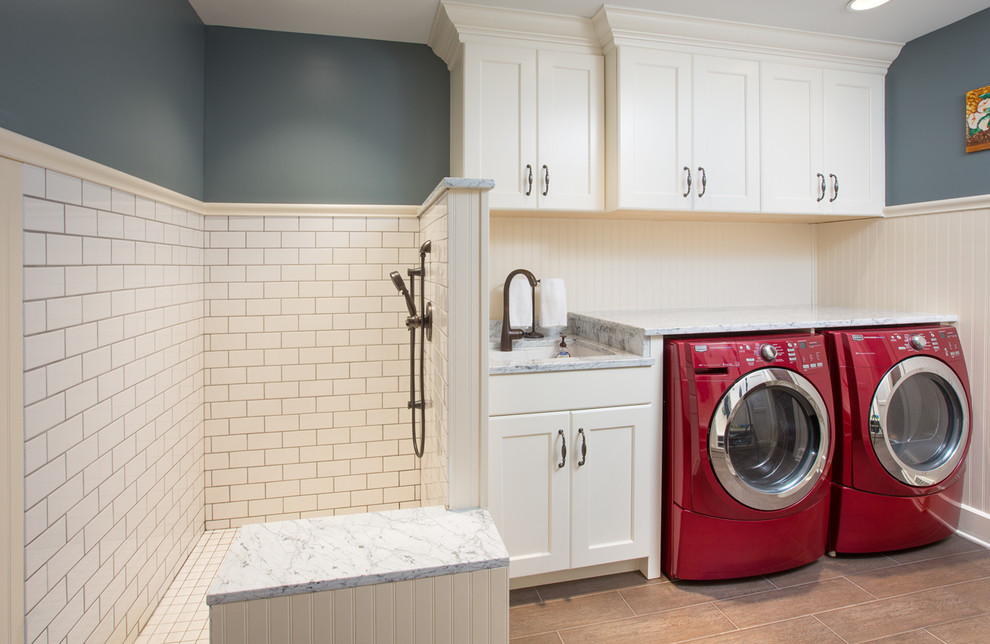 Photo of a mid-sized transitional single-wall utility room in Indianapolis with recessed-panel cabinets, white cabinets, marble benchtops, beige walls, porcelain floors, a side-by-side washer and dryer and beige floor.