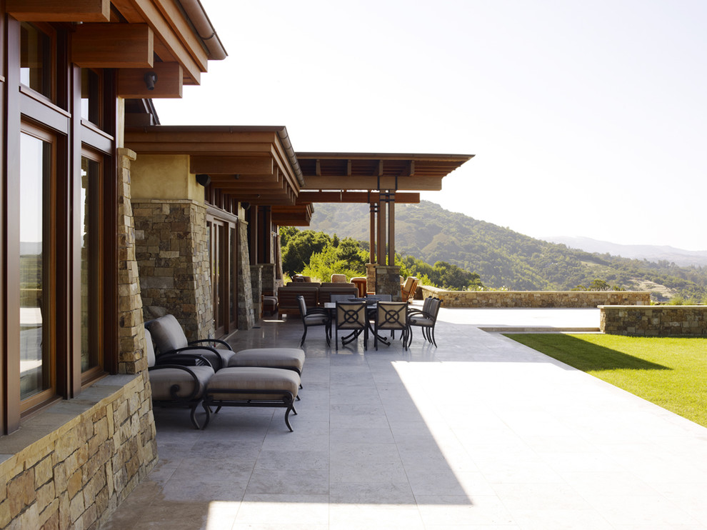 Photo of an expansive contemporary backyard patio in San Francisco with natural stone pavers and a roof extension.