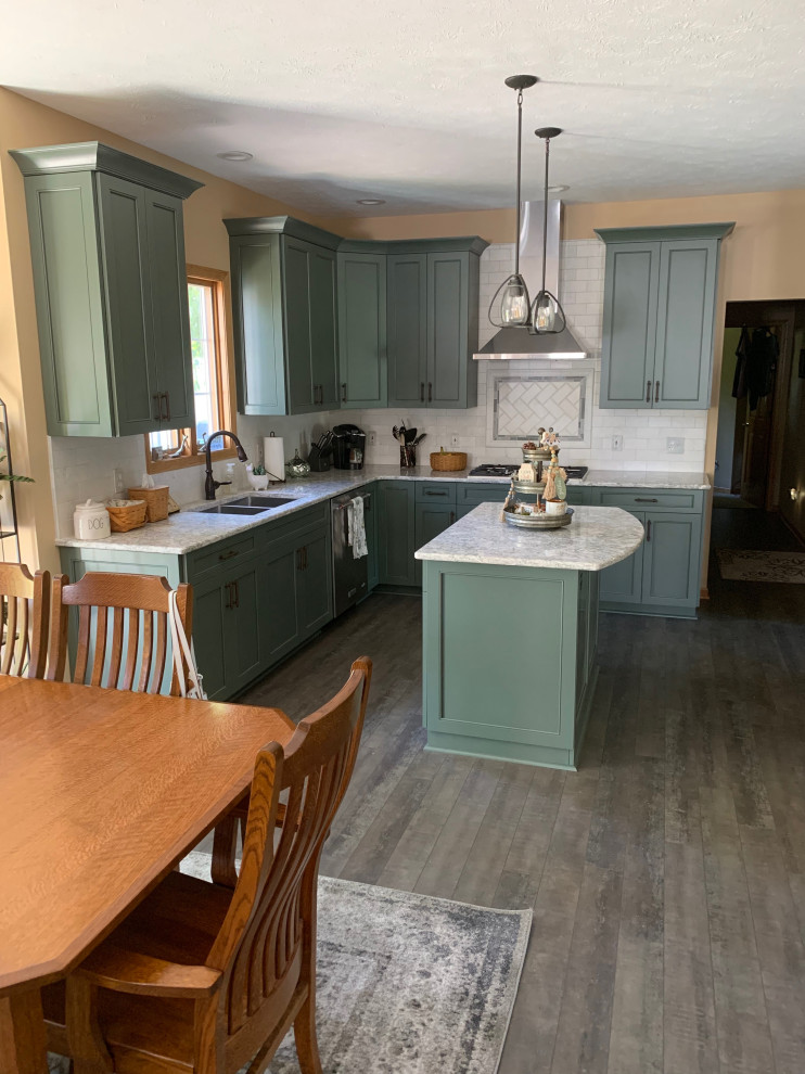 Inspiration for a mid-sized timeless l-shaped medium tone wood floor and brown floor eat-in kitchen remodel in Cleveland with an undermount sink, shaker cabinets, green cabinets, quartz countertops, white backsplash, subway tile backsplash, stainless steel appliances, an island and white countertops