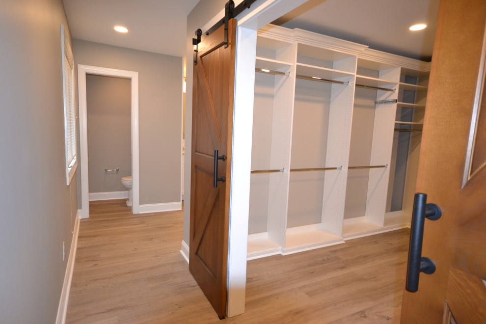 Design ideas for a large transitional gender-neutral walk-in wardrobe in Philadelphia with vinyl floors and brown floor.
