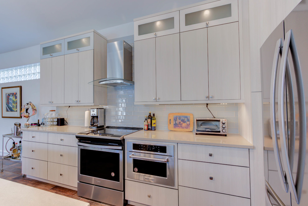 This is an example of a mid-sized contemporary l-shaped open plan kitchen in Other with an undermount sink, flat-panel cabinets, white cabinets, quartz benchtops, white splashback, porcelain splashback, stainless steel appliances and with island.