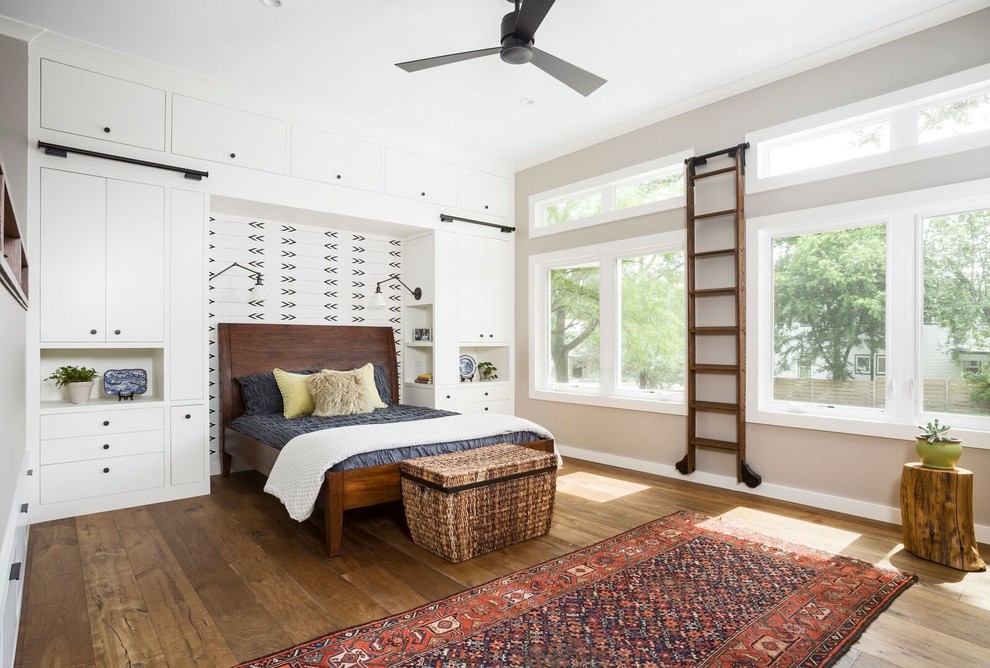This is an example of an expansive country master bedroom in Austin with beige walls, medium hardwood floors, no fireplace, a brick fireplace surround and brown floor.