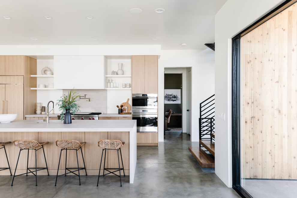 Mid-sized contemporary single-wall open plan kitchen in Salt Lake City with an undermount sink, flat-panel cabinets, light wood cabinets, quartzite benchtops, grey splashback, stainless steel appliances, concrete floors, with island, grey floor and grey benchtop.