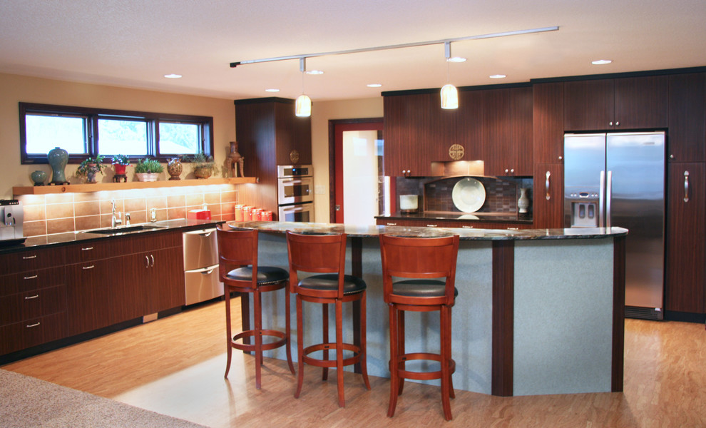Photo of a mid-sized asian l-shaped eat-in kitchen in Portland with flat-panel cabinets, dark wood cabinets, granite benchtops, metallic splashback, stainless steel appliances, cork floors, with island, an undermount sink and porcelain splashback.