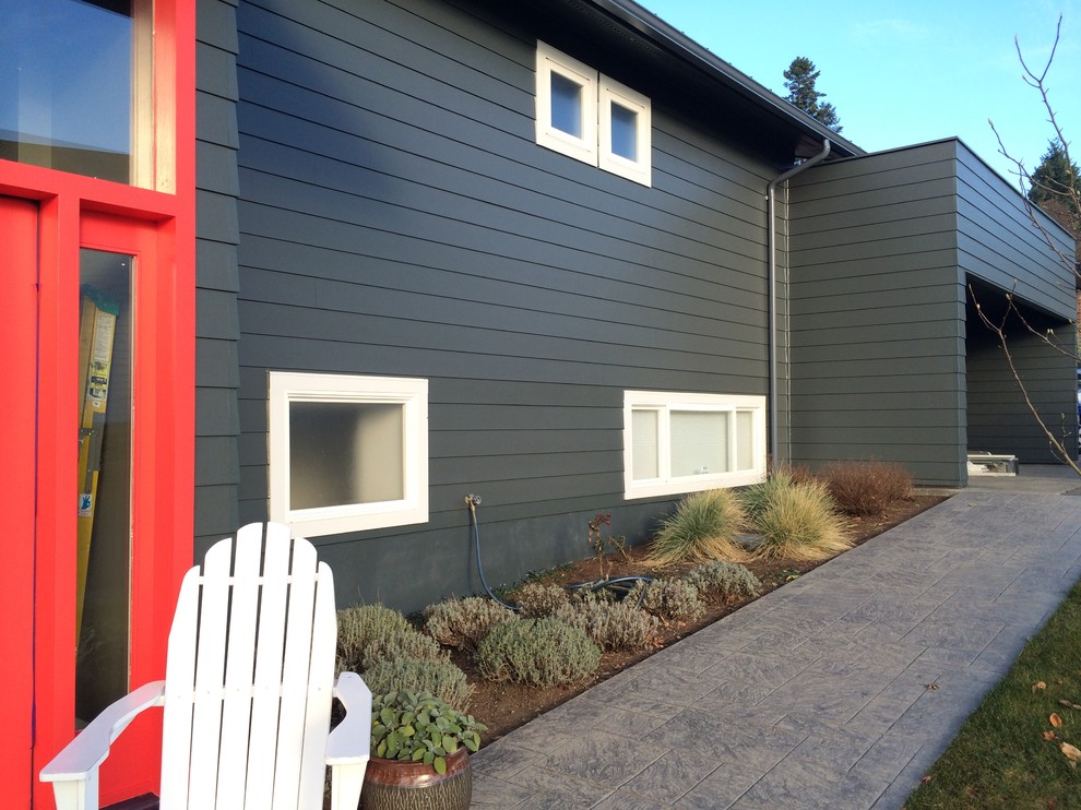 Mid-sized modern two-storey green exterior in Seattle with vinyl siding and a flat roof.