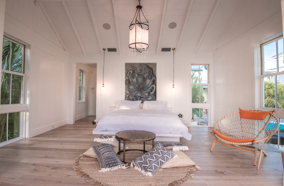 Photo of a large beach style master bedroom in Tampa with white walls, light hardwood floors and beige floor.