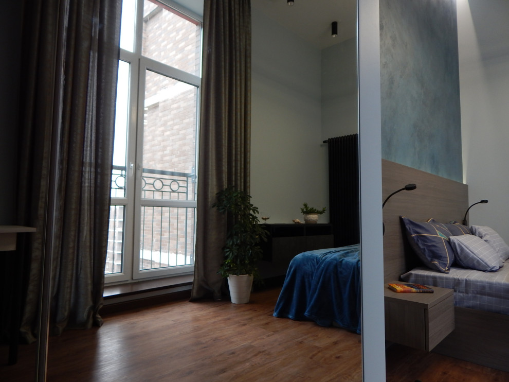 Ejemplo de dormitorio principal actual de tamaño medio con paredes multicolor, suelo laminado y suelo marrón