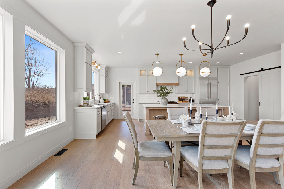Example of a large transitional medium tone wood floor and brown floor kitchen/dining room combo design with white walls