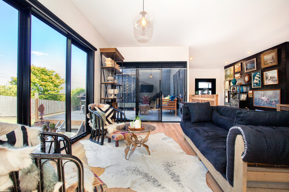Eclectic enclosed living room in Melbourne with white walls, light hardwood floors and no tv.