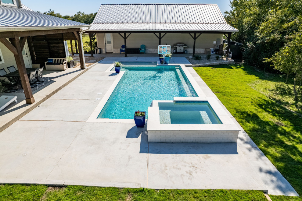 Exemple d'une piscine arrière moderne de taille moyenne et sur mesure avec un bain bouillonnant et des pavés en pierre naturelle.