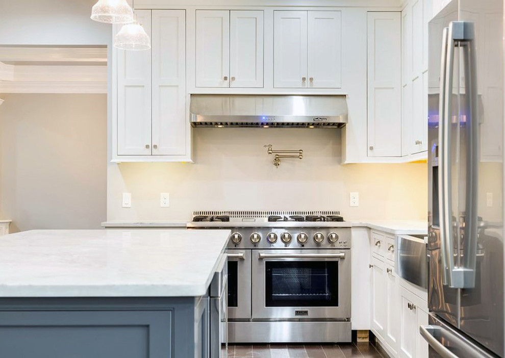 Inspiration for a large transitional l-shaped dark wood floor and brown floor kitchen pantry remodel with a farmhouse sink, recessed-panel cabinets, white cabinets, quartz countertops, stainless steel appliances, an island and white countertops