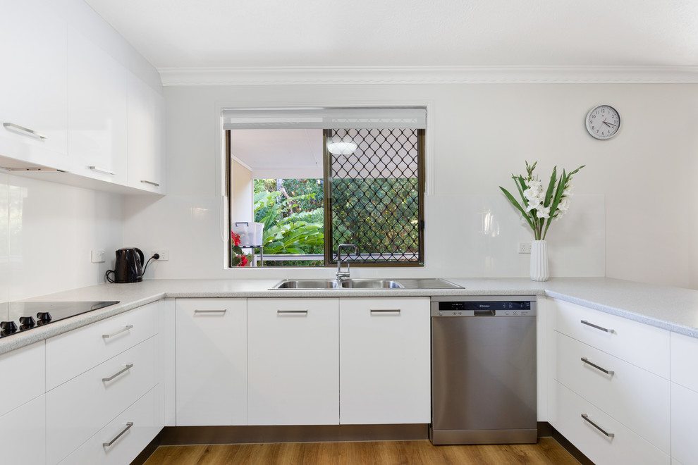 Large traditional u-shaped eat-in kitchen in Gold Coast - Tweed with a drop-in sink, flat-panel cabinets, white cabinets, laminate benchtops, white splashback, ceramic splashback, stainless steel appliances and grey benchtop.