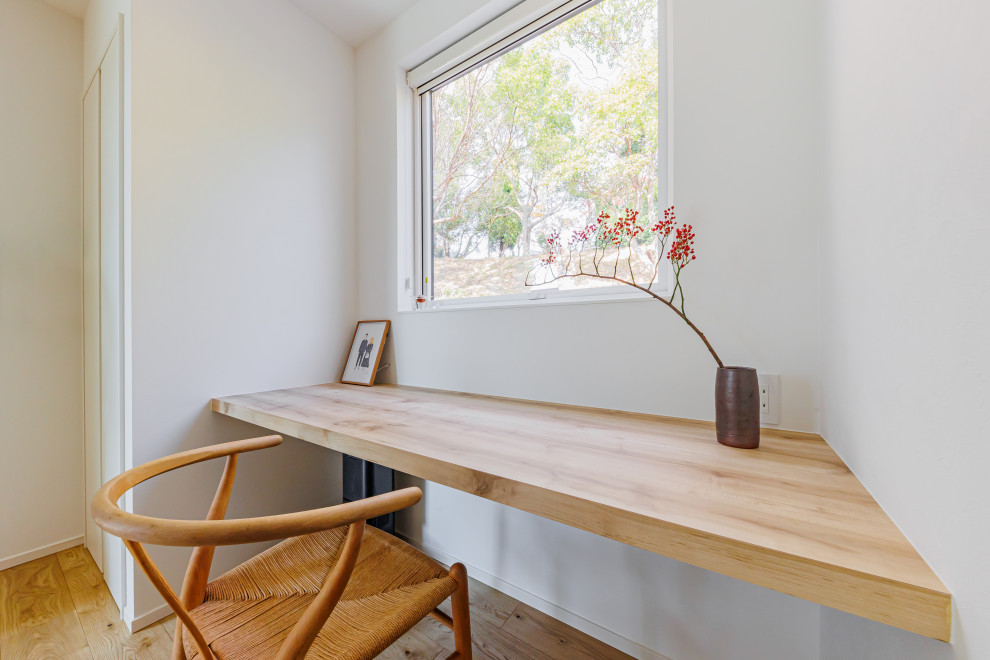 Réalisation d'un petit bureau minimaliste avec un mur blanc, un sol en bois brun, aucune cheminée, un bureau intégré, un sol marron, un plafond en papier peint et du papier peint.