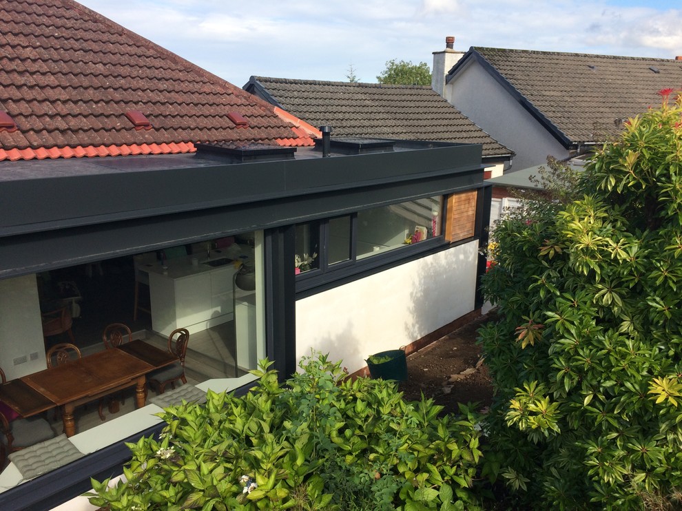 This is an example of a mid-sized contemporary one-storey stucco white house exterior in Glasgow with a flat roof.