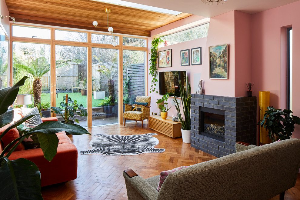 Design ideas for a midcentury living room in London with pink walls, a brick fireplace surround and brown floor.