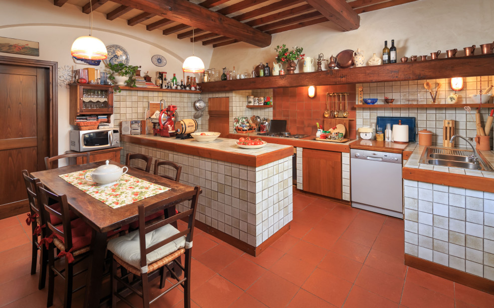 Inspiration for a mediterranean u-shaped kitchen in Florence with a double-bowl sink, white cabinets, tile benchtops, white splashback, white appliances, terra-cotta floors, with island, red floor, white benchtop and exposed beam.