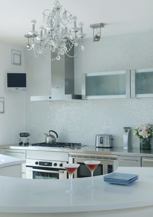 Photo of a mid-sized contemporary single-wall eat-in kitchen in Miami with stainless steel appliances, flat-panel cabinets, white cabinets, solid surface benchtops, white splashback, mosaic tile splashback and with island.