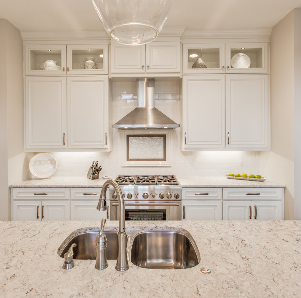 This is an example of a traditional eat-in kitchen in Jacksonville with an undermount sink, raised-panel cabinets, white cabinets, quartz benchtops, white splashback, subway tile splashback, stainless steel appliances, dark hardwood floors and with island.