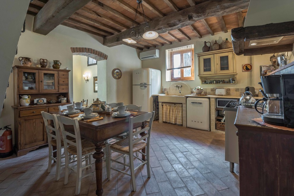 Photo of a mid-sized country l-shaped eat-in kitchen in Florence with a farmhouse sink, stone tile splashback and terra-cotta floors.
