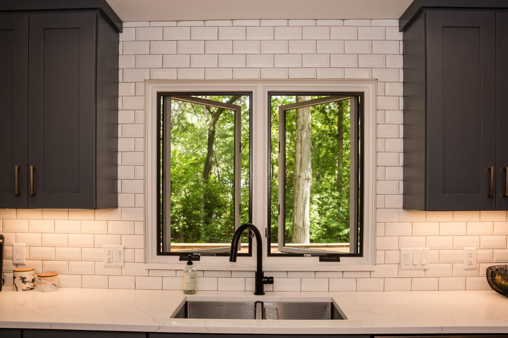 Mid-sized transitional galley medium tone wood floor and brown floor eat-in kitchen photo with an undermount sink, shaker cabinets, white cabinets, solid surface countertops, white backsplash, ceramic backsplash, stainless steel appliances, a peninsula and white countertops