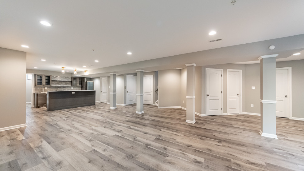This is an example of a large transitional open concept family room in DC Metro with a home bar, grey walls, vinyl floors, grey floor and no fireplace.