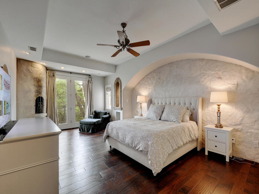 Inspiration for a mediterranean bedroom in Austin with white walls, dark hardwood floors and no fireplace.