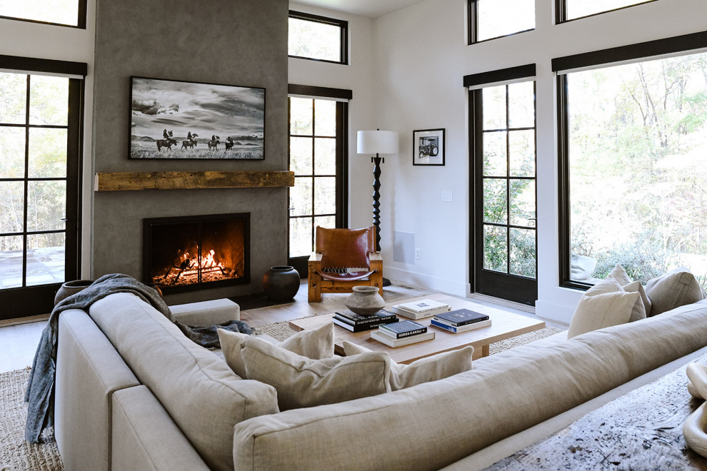 Idee per un grande soggiorno minimalista aperto con pareti bianche, parquet chiaro, camino classico, cornice del camino in intonaco e TV a parete