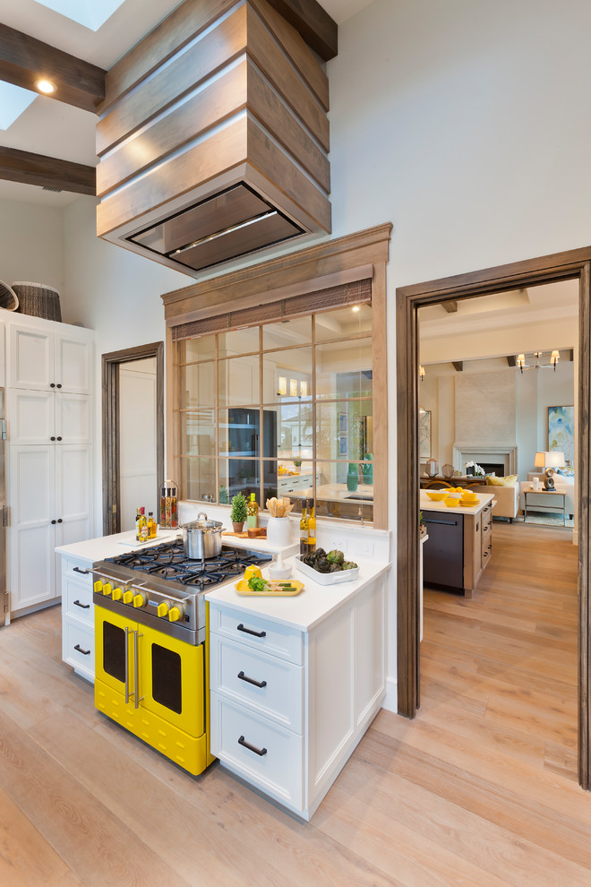 Inspiration for a large transitional u-shaped separate kitchen in Tampa with an undermount sink, shaker cabinets, white cabinets, solid surface benchtops, yellow splashback, subway tile splashback, stainless steel appliances, medium hardwood floors, brown floor and white benchtop.