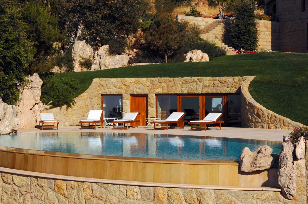 Inspiration for a mediterranean infinity pool in Other with a pool house.