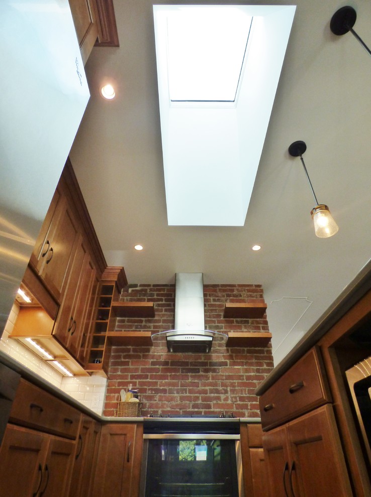 Example of a transitional l-shaped porcelain tile eat-in kitchen design with an undermount sink, recessed-panel cabinets, medium tone wood cabinets, quartz countertops, white backsplash, subway tile backsplash, stainless steel appliances and an island