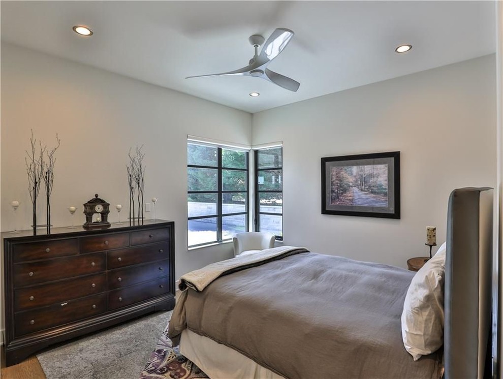 Photo of a mid-sized traditional guest bedroom in Dallas with beige walls, light hardwood floors, no fireplace and brown floor.