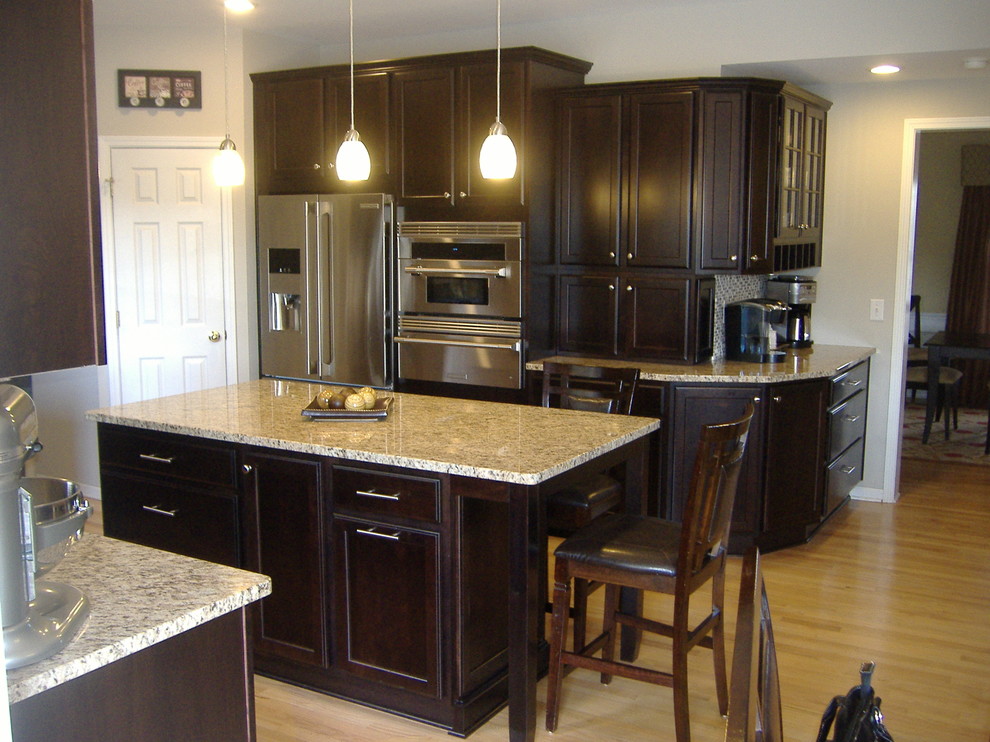 Example of a mid-sized transitional u-shaped light wood floor eat-in kitchen design in Indianapolis with an undermount sink, flat-panel cabinets, dark wood cabinets, granite countertops, stainless steel appliances, multicolored backsplash, glass tile backsplash and an island
