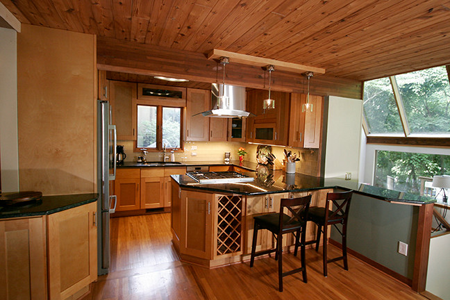 Eat-in kitchen - small transitional l-shaped porcelain tile eat-in kitchen idea with shaker cabinets, light wood cabinets, granite countertops, beige backsplash, glass tile backsplash, stainless steel appliances and a peninsula