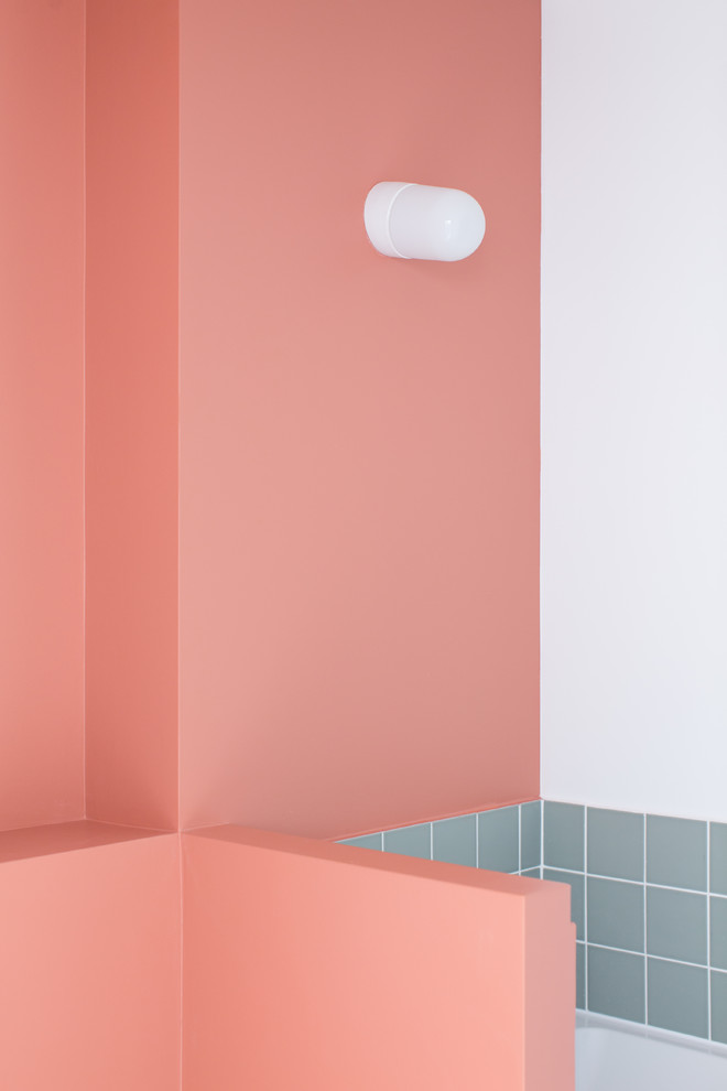 Cette image montre une petite salle de bain principale nordique avec des portes de placard blanches, WC suspendus, un carrelage blanc, un carrelage rose, des carreaux en allumettes, un mur blanc, sol en béton ciré, un lavabo encastré et un sol gris.