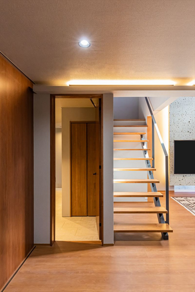 На фото: большая открытая гостиная комната в стиле модернизм с паркетным полом среднего тона, телевизором на стене, коричневым полом, деревянным потолком, обоями на стенах и серыми стенами без камина