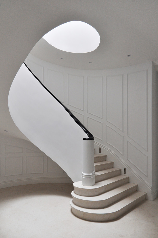 Photo of a large transitional curved staircase with wood railing.