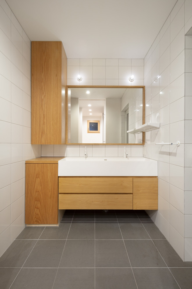 Exemple d'un petit WC et toilettes moderne avec un placard en trompe-l'oeil, des portes de placard blanches, un carrelage blanc, des carreaux de céramique, un mur blanc, carreaux de ciment au sol, un lavabo intégré, un plan de toilette en surface solide, un sol gris, un plan de toilette blanc et meuble-lavabo encastré.