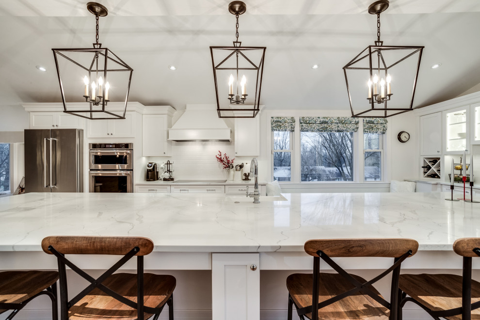 Example of a large transitional eat-in kitchen design in Baltimore with a farmhouse sink, shaker cabinets, white cabinets, quartz countertops, white backsplash, subway tile backsplash, stainless steel appliances, an island and white countertops