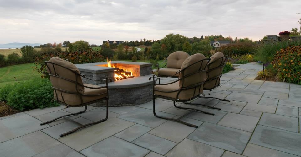 This is an example of a contemporary backyard full sun garden for summer in Burlington with a fire feature and natural stone pavers.