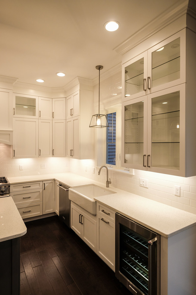 Inspiration for a large transitional u-shaped dark wood floor and brown floor eat-in kitchen remodel with a farmhouse sink, recessed-panel cabinets, white cabinets, quartz countertops, white backsplash, stainless steel appliances, an island and white countertops