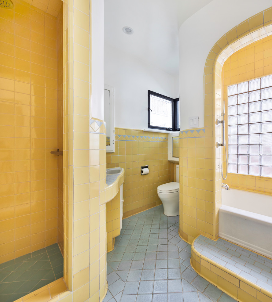 Idéer för mellanstora medelhavsstil blått badrum för barn, med luckor med upphöjd panel, gula skåp, ett badkar i en alkov, en dusch i en alkov, en toalettstol med hel cisternkåpa, gul kakel, keramikplattor, gula väggar, klinkergolv i keramik, ett undermonterad handfat, kaklad bänkskiva, blått golv och med dusch som är öppen