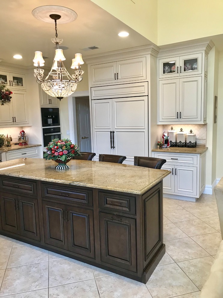Inspiration for a large traditional l-shaped eat-in kitchen in New York with a farmhouse sink, beaded inset cabinets, white cabinets, granite benchtops, white splashback, marble splashback, stainless steel appliances, porcelain floors, with island and beige floor.